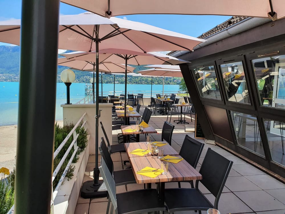 La terrasse du restaurant, tables et parasols face à l'eau